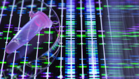 Image of a small sample tube in front of a screen covered in fluorescent bands that represent DNA sequences.
